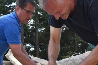 Ein Blockhaus für die "Wald-Schule" - Kajo Lange (r.) und Maik Kunz verlegen die Dämmung an Schnittflächen und befestigen sie am Stamm.