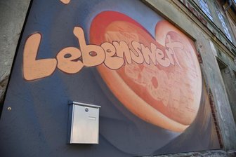 Ein Briefkasten als Lostrommel: Wie die Adorfer zu Gewinnern werden können - Das Banner am Gebäude der ehemaligen Wolfsschlucht in Adorf weist auf die Gutschein-Aktion in Adorf hin. Der Briefkasten fungiert als Lostrommel.