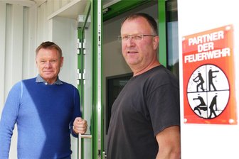 Ein Herz für die Feuerwehr: Unternehmen im Erzgebirge beschäftigt zehn Feuerwehrleute - Ein Bild mit Symbolcharakter für einen Partner der Feuerwehr: Zabag-Geschäftsführer Michael Simon hält dem Grünhainichener Wehrleiter Hendrik Winkler die Tür auf.