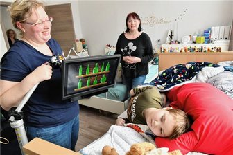 Ein Junge kämpft sich zurück ins Leben: "Mensch, Jaden, du gibst heute alles!" - Logopädin Bettina Fritzsche mit dem Gridpad: Mit seinen Augen steuert Jaden (im Hintergrund Mutter Manuela) das Zielwerfen auf die Flaschen. 