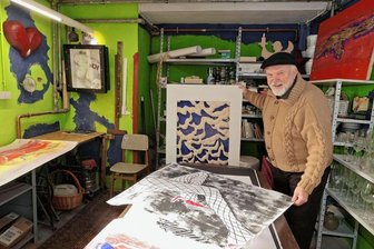 Ein Keller voll Kunst und Trödel - Peter Uhlmann in einem der Kellerräume, die er als Trödelmarkt und Atelier zugleich nutzt. Seine Motive sind oft erotisch, bekannt wurde er zuletzt mit dem Kalaschnikow-Motiv (rechts oben).