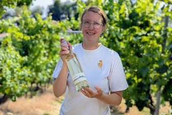 Ein Prosit auf den Müller-Thurgau - Jungwinzerin Rebecca Röhrenbach mit einer Flasche Müller-Thurgau. Der Name „Albert“ erinnert an ihren Urgroßvater, der im Schmuggelboot saß.