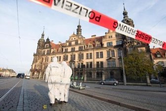 Einbruch in Grünes Gewölbe: Polizei nimmt Tatverdächtige in Berlin fest - Zwei Mitarbeiter der Spurensicherung stehen im November 2019 vor dem Dresdner Residenzschloss mit dem Grünen Gewölbe hinter einem Absperrband.