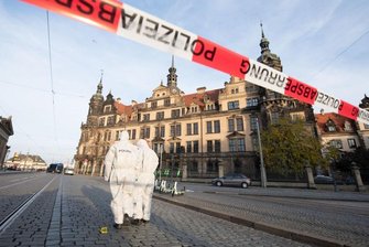 Zwei Mitarbeiter der Spurensicherung stehen vor dem Residenzschloss mit dem Grünen Gewölbe hinter einem Absperrband.