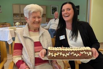 Eine Erzgebirgerin feiert 100. Geburtstag: Wie ein Bahnsteig ihr Leben veränderte - Haben gut lachen: Eine Torte gab’s für Jubilarin Erika Bräuer von Einrichtungsleiterin Katrin Prezewowsky vom Carolahof in Freiberg.