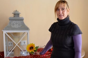 Eine Kerze und eine Blüte zur Erinnerung - Silvia Oehme mit der Laterne, in der bei Todesfällen die Kerze angezündet wird. Die Sonnenblume, auf der die Namen der Verstorbenen verewigt wird, wird derzeit von einem Tischler hergestellt.