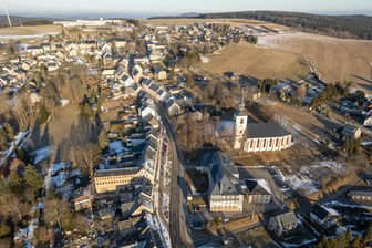 „Eine nie dagewesene Haushaltslage“ – Bergstadt im Erzgebirge steckt tief in roten Zahlen - Jöhstadt – vorn rechts an der Straße die Oberschule und die St.-Salvator-Kirche – stehen schwere Zeiten bevor. Die Bergstadt ist einmal mehr in Finanznot geraten.
