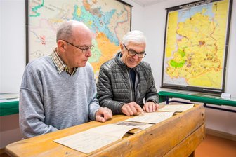 Eine Zeitreise durch Adorfer Bildungsgeschichte - Alte Ranzen, Karten, Dokumente, Schulhefte. Bernd Lohse (l.) und Vereinsvorsitzender Roland Rößler stöbern in der Vergangenheit.