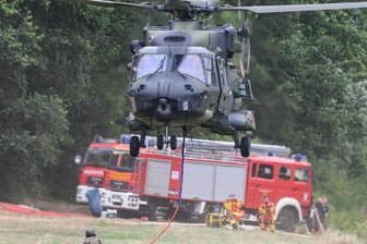 Einsatzkräfte sind in Alarmbereitschaft - Auch die Bundeswehr unterstützt mit ihren Kräften die Brandbekämpfung im Naturpark - hier im Foto ein Hubschrauber, der mit einem Löschwasser-Außenlastbehälter am Ufer der Elbe abhebt.