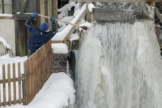 Eisige Schönheit im Erzgebirge: Frost verzaubert Wasserräder im Frohnauer Hammer - Auch Museumsführer Jörg Bräuer kann gegen das Eis wenig ausrichten.