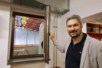 Eispiraten Crimmitschau: Neue Kabine für Gäste-Teams, die kurz vor dem ersten Bully viel mehr Lärm aus dem Fanblock hören - Fachbereichsleiter Stefan Aurich öffnet das Fenster in der neuen Kabine für die Gäste-Mannschaften, die nun direkt ins Stadion schauen.