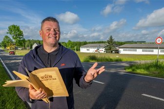 Elf Jahre Dornröschenschlaf: Was wird aus dem Gewerbegebiet an der B 101? - Enrico Klemm hält die Bauunterlagen des Gewerbegebietes Schulstraße/B 101 aus DDR-Zeiten in den Händen. Im Hintergrund stehen die Hallen an der Bundesstraße in Mittelsaida.