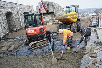 Elsterberger Burgruinen-Bühne erhält neuen Fußboden - Mit dem Dumper (rechts hinten) wurde der Beton vom Vormischer, der aus Platzgründen im Stadtgebiet stand, auf die Burgruine gefahren, dort mit dem Minibagger abgeladen und eingebaut. Gut 200 Kubikmeter Beton für zwei Schichten werden so bewegt.