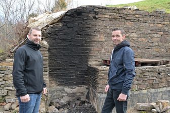 Empörung in Stadt im Erzgebirge: Schmierereien und Zerstörungen an öffentlichen Anlagen - Marcus Hofmann (li.) und Kai Ebert vom Museums- und Geschichtsverein Aue, der sich um die Reste des ehemaligen Freibades Hakenkrümme in Aue kümmert. Dort hat es in den letzten Tagen Vandalismus gegeben. Der Mauerrest zeigt die Spuren des gelegten Feuers.