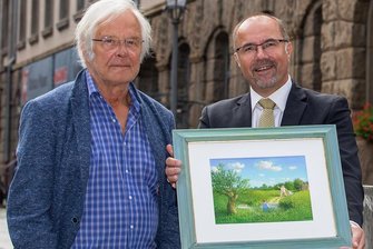 Endlich eine Mutter für Ohsers Vater und Sohn - Michael Sowa übergibt an Kulturbürgermeister Steffen Zenner (CDU) das fertig gestellte Bild, das er mit dem Eintrag in das Goldene Buch der Stadt begonnen hatte. Vater und Sohn laufen auf eine im Teich stehende Frau zu: "Mutti!"