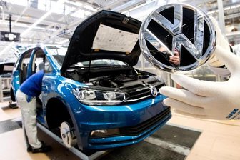 Erfolgsprämie für VW-Mitarbeiter steigt auf 4750 Euro - Ein Mitarbeiter zeigt ein VW Logo kurz vor Einbau in einen Volkswagen Touran.