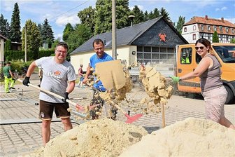 Erlau: Warum zum Dorffest mit dem Fußball auf die Dartscheibe geschossen wird - Am Mittwoch ist am Feuerwehrdepot in Erlau mit dem Aufbau für das Dorffest begonnen worden. Matthias Strauß (v. l.), Philipp Wähner und Heike Hoffmann von der Initiative für Erlau verteilen Sand und sorgen so für Strandfeeling an der Bar.