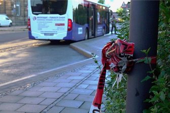 Zusammengeknotetes Absperrband der Polizei hängt noch an einem Pfahl an einer Bushaltestelle in Hof. In der Nähe wurde ein Busfahrer tödlich verletzt.