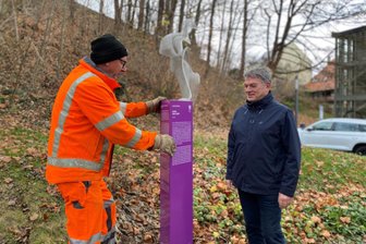 Erst Abfuhr, jetzt Ankunft: Augustusburg bekommt sein Purple-Path-Kunstwerk - Bauhof-Mitarbeiter (im Bild Andreas Horbach und Bürgermeister Jens Schmidt) haben am Donnerstag die Purple-Path-Skulptur „Inside“ (im Hintergrund) mit der Info-Stele aufgestellt.