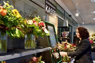 Erster 24-Stunden-Blumenshop in Chemnitz eröffnet - Doreen Voigt demonstriert, wie Kunden ihre Blumen im 24/7 Shop einscannen und bezahlen können.