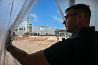 Erster Einblick in die neue Grundschule in Neukirchen im Erzgebirge - Bürgermeister Sascha Thamm blickt aus dem Flur des neuen Neukirchener Schulgebäudes auf den Hinterhof und den Hort-Rohbau.