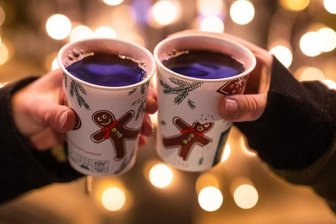 Zwei Besucherinnen eines Weihnachtsmarktes stoßen mit Glühwein an.
