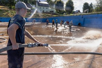 Erzgebirge: Folgen der Flut lassen Steinbach nicht los - Moritz Fritzsch und zahlreiche andere Freiwillige reinigten am Donnerstag das Becken des Steinbacher Freibads.