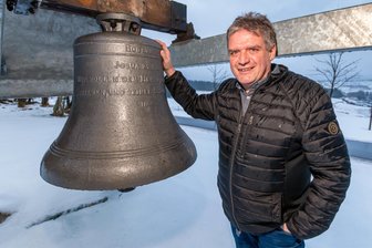 Erzgebirge: Warum in diesem Jahr im äußersten Landkreiszipfel groß gefeiert wird - Deutschneudorfs Bürgermeister René Hoffmann an einer zum Glockenwanderweg gehörenden Glocke im Ortsteil Brüderwiese. In der Gemeinde werden in diesem Jahr gleich zwei große Jubiläen gefeiert.