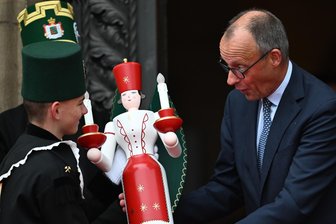 Erzgebirger begrüßen Bundeskanzler Merz mit Steigerlied und überreichen Präsent - Bundeskanzler Friedrich Merz erhält von Benjamin Schott einen erzgebirgischen Engel.