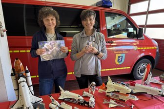 Erzgebirger im Weltraum-Fieber: Warum ein ganzes Dorf plötzlich hunderte Raumschiffe bastelt - Romy Mothes zeigt ein Foto des Astronauten Alexander Gerst. Und Sandra Heymann hält ein kleines Raumschiff, das jenen Deutschen 2018 ins All begleitet hat (v. l.).