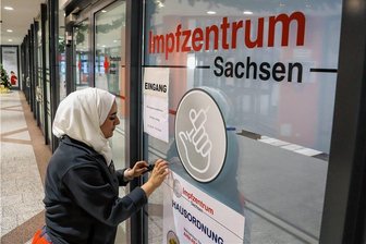 Erzgebirgs-Impfzentrum in Aue schließt: Der Letzte räumt die Impfstelle auf - Afaf Hab Kassem entfernte am Mittwoch im Eingangsbereich der Impfstelle die Aufkleber an den Scheiben.