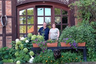 Erzgebirgsfeeling pur – und das mitten in Niedersachsen - Dort, wo vor Heike und Wolfgang Lorentz Blumenkästen stehen, leuchtet in der Adventszeit ein großer Schwibbogen. Aber nicht nur den haben sich die beiden Niedersachsen aus dem Erzgebirge mitgebracht. Labrador Retriever „Socke“, der hier gerade unter dem Holzbalken hervorspringt, stammt aus einer Zucht in Olbernhau.