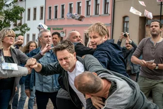 Erzgebirgskrimi: Wie eine Kirchbergerin ihre Stadt filmreif macht - Maik in Not: Kommissar Robert Winkler (Kai Scheve, 3.v.r.) muss Maik (Adrian Topol, M.) aus einer brenzligen Situation auf dem Marktplatz retten. Hinten links mit den langen Haaren als Teil der wütenden Menge: Die Kirchbergerin Yvonne Scheithauer. 