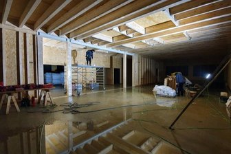 Es geht voran: Neue Schule in Grünhainichen nimmt Gestalt an - Über dem Mittelbau der Grundschule befinden sich bereits die Dachbalken sowie die OSB-Platten. Im Hintergrund ist ein Klassenzimmer zu sehen, in dem die Fenster und Türen bald eingebaut werden.