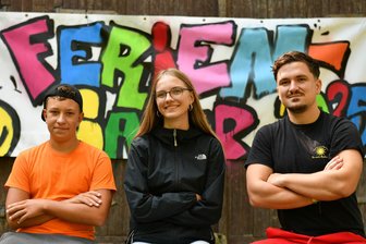 „Es ist kein blöder Sommer“: Fünf Tipps zum Regenwetter aus dem Feriencamp Rochlitz - Im Feriencamp des VfA Rochlitzer Berg in Biesern trotzen auch Lennes (l.), Lina und Wochenleiter Clemens Spiller dem Regen.