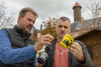 Ex-Skispringer reinigte Auerbachs Glühweintassen - doch damit ist nun Schluss: Wer diesmal den Spüljob auf dem Weihnachtsmarkt übernimmt - Citymanager Uwe Prenzel (links) und Grafiker Heiko Ebert von „HE Design“ begutachten den Prototyp der diesjährigen Glühweintasse. Ebert hat das Motiv entworfen. 5000 gelbe Tassen wurden bestellt. 2023 war die Tasse dunkelblau.