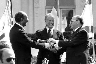 Ex-US-Präsident Jimmy Carter: Der gute Mensch von der Erdnussfarm - Der ägyptische Präsident Anwar Sadat (l), US-Präsident Jimmy Carter (M) und der israelische Ministerpräsident Menachem Begin reichen sich auf dem Nordrasen des Weißen Hauses die Hände, nachdem sie den Friedensvertrag zwischen Ägypten und Israel am 26. März 1979 in Washington unterzeichnet haben.