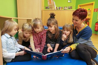 Experten aus Meerane: Fünf Bücher, die Kindern gut tun - Erzieherin Katrin Gamon sitzt mit den Mädchen und Jungen in einer Leseecke in der Kindertagesstätte „St. Martin„ in Meerane.