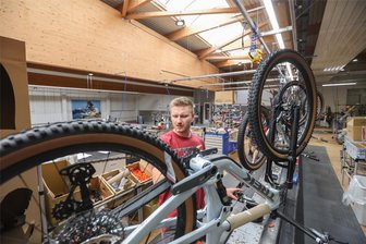 Fahrradhersteller Diamant in Hartmannsdorf fährt Produktion wieder hoch - Tim Kohlbach montiert ein Fahrrad der Marke Trek. Der 24-Jährige war 2022 Sachsens bester Lehrling und zeigt auch mit seinem gezwirbelten Schnurrbart die fast 140-jährige Diamant-Tradition.