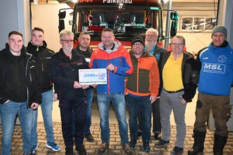 Falkenauer Skiclub überwältigt von Welle der Unterstützung nach Diebstahl: „Damit hatten wir nicht gerechnet“ - Die Feuerwache Falkenau als Schauplatz einer Benefizaktion für den Skiverein: Thomas Richter, links, übergibt den symbolischen Spendenscheck an Jens Thierbach vom Skiverein im Beisein der Initiatoren.