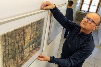 Falkenstein erinnert an Lothar Weller: Welche Rätsel der malende Eisenbahner den Vogtländern hinterließ - Bernd Seidel von falkart beim Aufbau der Werkschau „Streifzüge“. Sie widmet sich der Eisenbahn- und Landschaftsmalerei von Lothar Weller. Zu sehen von diesem Donnerstag (Vernissage 17 Uhr) bis März 2025 in Falkenstein.
