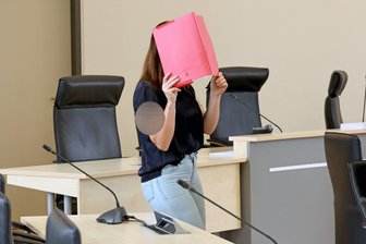 Fall Fabian: Sprach die Angeklagte ein Alibi ab? - Die Angeklagte betritt den Gerichtssaal mit rotem Aktendeckel vor dem Gesicht.