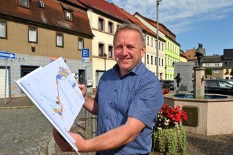 Fast 19 Millionen Euro für die Stadtsanierung: Was Lunzenau und Oederan damit vorhaben - Bürgermeister Ronny Hofmann auf dem Markt in Lunzenau mit dem Plan zur Stadtsanierung.