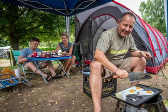 Faszination Kriebsteinsee: Familie aus Rochlitz schlägt hier seit Jahren ihre Zelte auf - Familie Bergner beim Frühstück in Lauenhain: Jörg Bergner brät Spiegeleier auf einer Stahlplatte, die vom Grill erhitzt wurde.