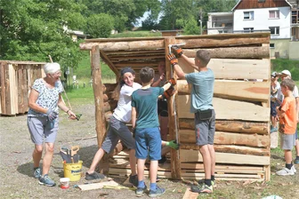Ferienkinder bauen in Reichenbach Holzbuden - Am Ferienprogramm „Holz-Buden-Bau“ der Sektion „Kinner-Dorf-Dratsch“ des Vereins Dorfclub Reichenbach Holzbudenbau am Sportplatz in Reichenbach nehmen 20 Kinder teil, hier mit Leiterin Bärbel Vogel (links) an der Spitze und Kerstin Dornig vom Kinderschutzbund Freiberg. r