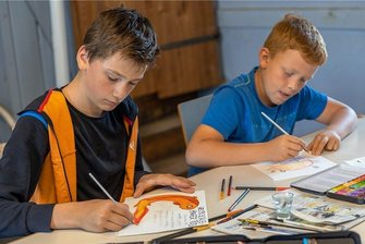Ferienkinder erschaffen neue Fantasiewesen auf Burg Mylau - Fantasiegeschöpfe nehmen Gestalt an: Xavier Wunderlich (links) hat sich den Fisch "Gelbschleimiger Tod" ausgedacht. Alexander Lehmann (rechts) malt eine Axolotl-Qualle mit Kiemenästen am Schirm. 