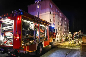 Feuerwehr rückt zu Wohnungsbrand im Erzgebirge aus - Polizei ermittelt wegen Brandstiftung - Die Einsatzkräfte vor dem Wohnblock in Raschau-Markersbach, in dem in einer Wohnung Mobiliar gebrannt hat.
