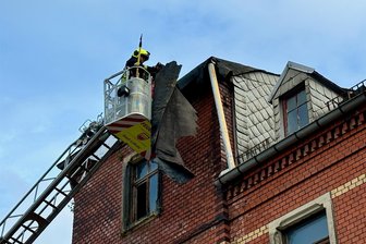 Feuerwehreinsatz im Erzgebirge: Von leer stehendem Haus geht Gefahr aus - Von der Drehleiter aus wurden die losen Teile entfernt.