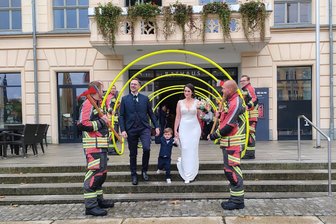 Feuerwehreinsatz vorm Zwickauer Rathaus: Schlauchbogen-Spalier empfängt frisch Vermählte - Maximilian Thiele, seine Frau Alice und Sohn Fritz werden vorm Rathaus von Kameraden der Feuerwehr Reinsdorf empfangen.