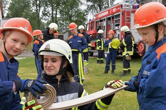 Feuerwehren in Mittelsachsen dürfen wieder Nachwuchs ausbilden - Beim ersten Dienst der Freiberger Kinder- und Jugendfeuerwehr in Freiberg nach der Coronapause: Die 16-jährige Gymnasiastin Emely Rausch (Mitte), seit 2016 in der Feuerwehr aktiv, übt mit Paula (links) und Clara das Schlauch-Einrollen. Emely Rausch unterstützt seit März diesen Jahres die Jugendarbeit in der FFW Freiberg.